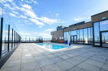A rooftop pool area with a glass railing and a clear blue sky.